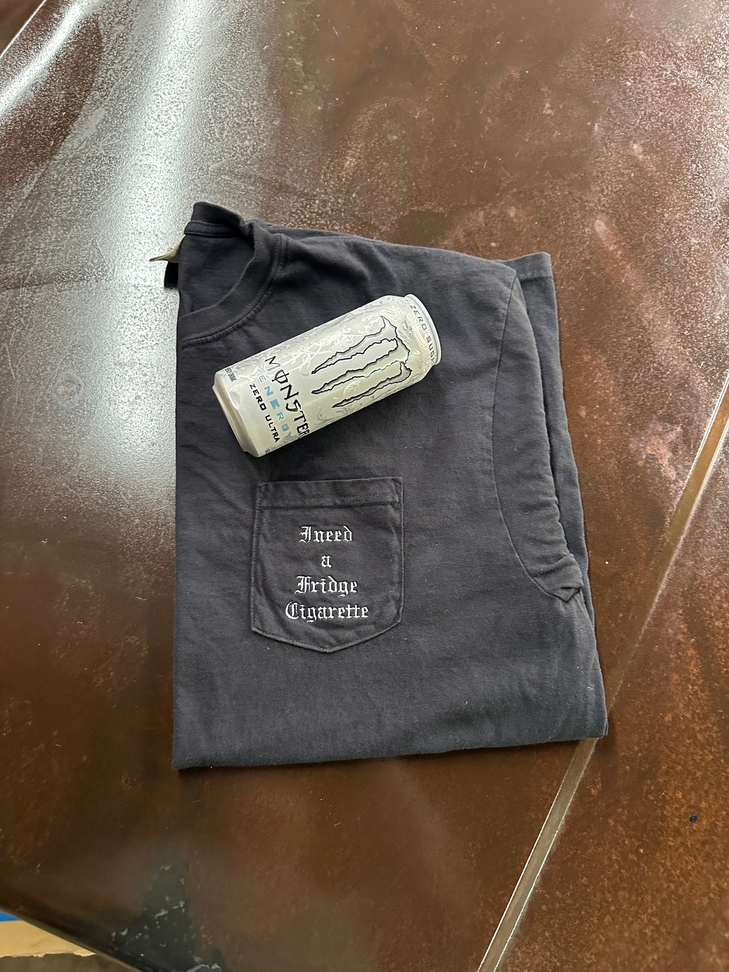 Folded black shirt with a Monster Energy drink can, i need a fridge cig  