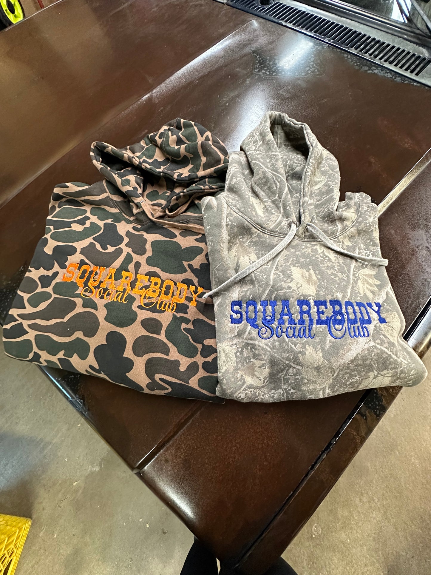 Camo-patterned hoodie with 'Square body' branding on a truck surface.